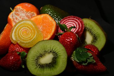 Siyah arka planda sarılmış jöleli meyve ve sebze çeşitleri