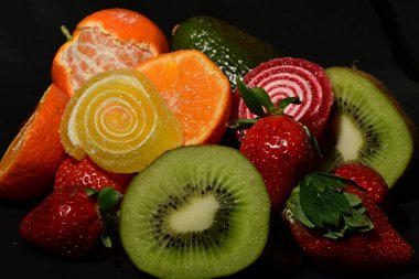 Siyah arka planda sarılmış jöleli meyve ve sebze çeşitleri