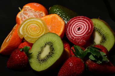 Siyah arka planda sarılmış jöleli meyve ve sebze çeşitleri