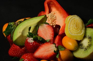 Siyah arka planda sarılmış jöleli meyve ve sebze grubu.