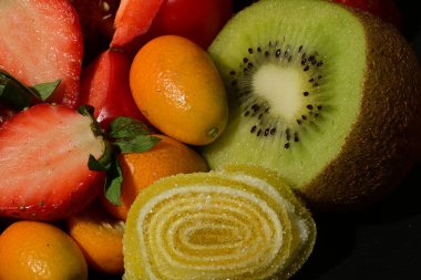 Siyah arka planda sarılmış jöleli meyve ve sebze grubu.