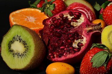 Siyah arka planda sarılmış jöleli bir grup meyve.