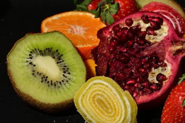 Siyah arka planda sarılmış jöleli bir grup meyve.