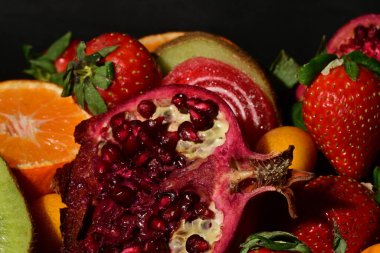 Siyah arka planda sarılmış jöleli bir grup meyve.