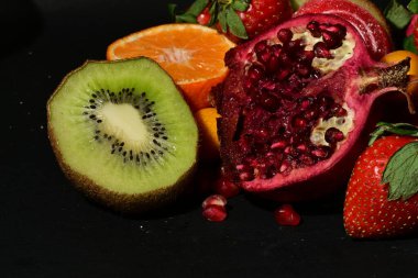 Siyah arka planda sarılmış jöleli bir grup meyve.