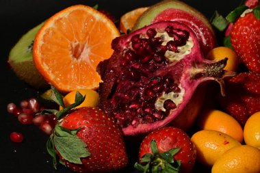 Siyah arka planda sarılmış jöleli bir grup meyve.