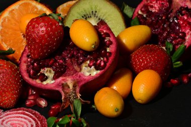 Siyah arka planda sarılmış jöleli bir grup meyve.