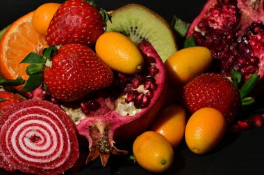 Siyah arka planda sarılmış jöleli bir grup meyve.