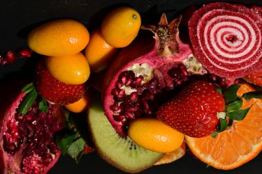 Siyah arka planda sarılmış jöleli bir grup meyve.