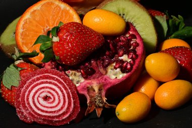 Siyah arka planda sarılmış jöleli bir grup meyve.