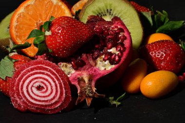 Siyah arka planda sarılmış jöleli bir grup meyve.