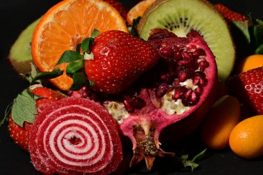 Siyah arka planda sarılmış jöleli bir grup meyve.