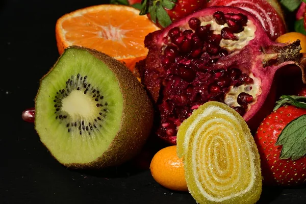 Siyah arka planda sarılmış jöleli bir grup meyve.