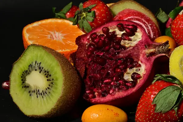 Siyah arka planda sarılmış jöleli bir grup meyve.