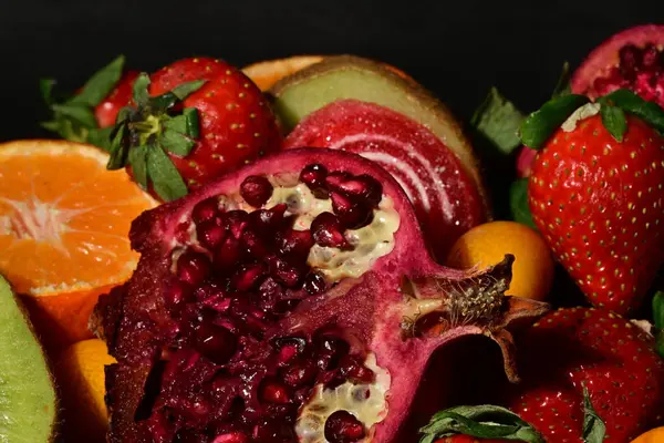 Siyah arka planda sarılmış jöleli bir grup meyve.