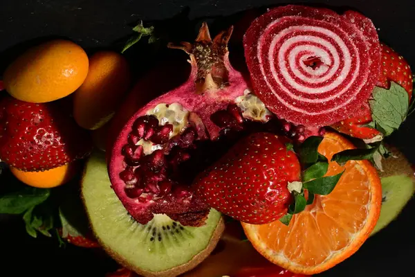 Siyah arka planda sarılmış jöleli bir grup meyve.