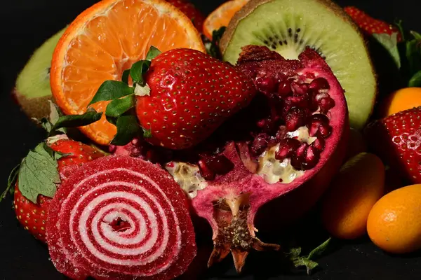 Siyah arka planda sarılmış jöleli bir grup meyve.