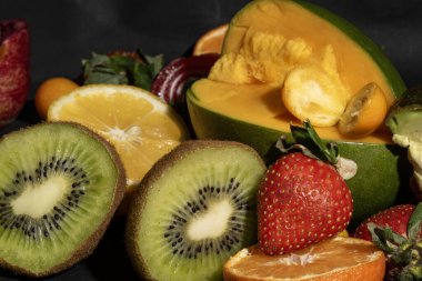 Siyah arkaplanı olan bir yığın meyve.