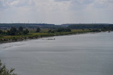 Arka planda bitki örtüsüyle kaplı bir nehir manzarası.
