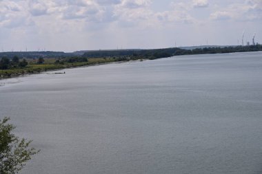 Arka planda bitki örtüsüyle kaplı bir nehir manzarası.