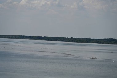 Arka planda bitki örtüsüyle kaplı bir nehir manzarası.