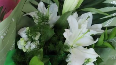 Beyaz zambaklar, güller ve yeşil bitkiler.