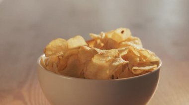 Potato chips  in white bowl on wooden table , hands take chips  ,party time