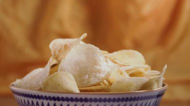 Potato chips  in white bowl on wooden table , hands take chips  ,party time