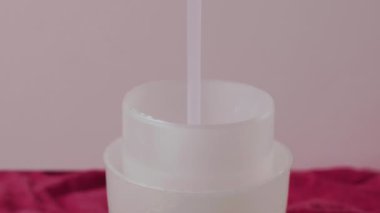Plastik kaskete dökülen pembe sıvı çamaşır deterjanı. ,