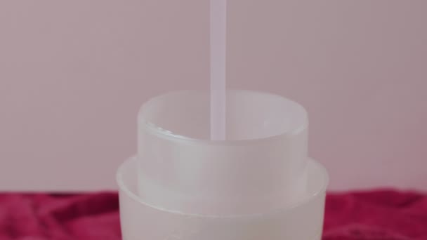 ピンクの液体洗濯洗剤の流れはプラスチック製の測定帽子に注ぎました — ストック動画