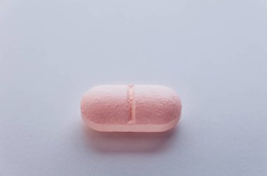 Beyaz masada pembe ilaç hapı, ocak bakımı ve ilaç.