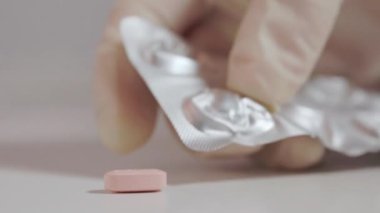 Elle ameliyat eldiveni hikayeleri. Su toplamış paketten pembe ilaç hapı. Sağlık sigortası ve ilaç konsepti., 