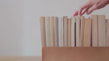 Karton kutudan kitap arayan bir kadın, okula, iş yerine geri dönüyor.