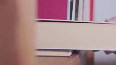 Kadın eli kitapları ahşap rafa koyuyor, kendi kendine çalışıyor, yaşam tarzı okuyor ya da okula geri dönüyor.