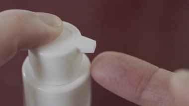 Kadın parmağının beyaz kozmetik şişeye basıp vücut yağı, vücut bakımı ve güzellik tedavisinin ayrıntıları.