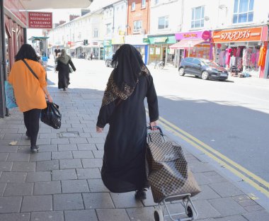  Müslüman kadınlar güneşli bir günde İngiliz şehrinden alışveriş yapıyorlar..