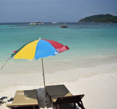 Güneş şemsiyesi ve sandalyeler muhteşem kumsalda.