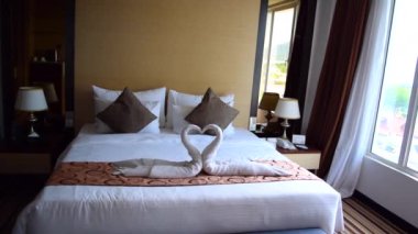 Otel odasının içi toprak renginde ve yatakta romantik kalp süslemeleri var..