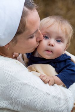 Anne, sekiz aylık mavi gözlü oğlunu şefkatle öpüyor.