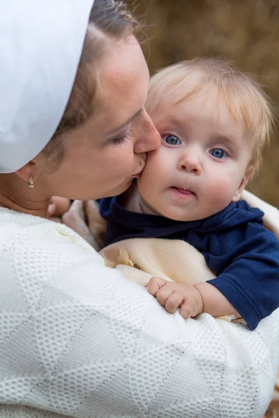 Mother tenderly kisses her eight-month-old blue-eyed son
