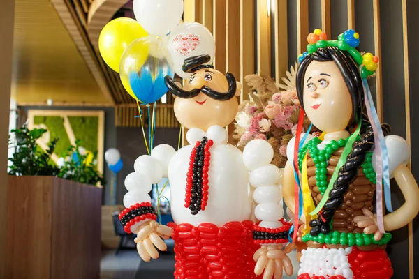 Ukrainian bride and groom made of multi-colored balloons stand holding hands at the entrance to the room