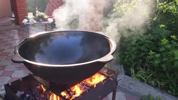 ウズベキスタン料理のピラフ グリル上の鋳鉄釜で植物油を加熱する — ストック動画
