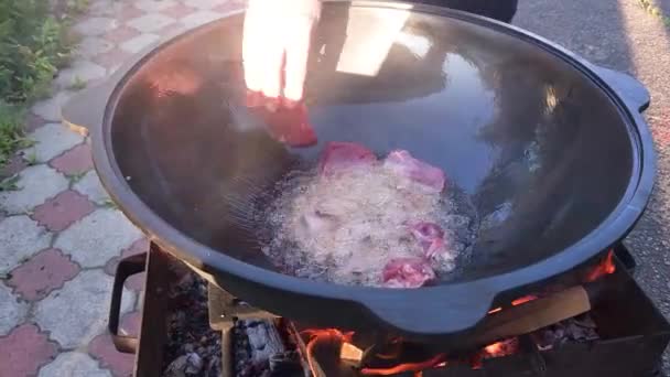 做饭乌兹别克皮拉夫 在热植物油中加入鲜肉 放在烤架上的铸铁大锅中煎 — 图库视频影像