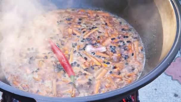 ウズベキスタン料理のピラフ グリルに鋳鉄製の釜でZirvakを沸かす — ストック動画