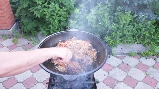 ウズベキスタン料理のピラフ 少し煙とグリルに立って鋳鉄製の釜に完成したピラフを放映し — ストック動画