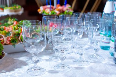 Beyaz bir masa örtüsünün üzerinde kırmızı balık, avokado ve otlarla aperatiflerle dolu beyaz bir masa örtüsü üzerinde bir grup kristal şarap kadehi.