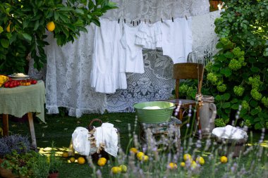 Beyaz kadınların çamaşırları, limonların, çiçeklerin ve sebzelerin ve diğer yiyeceklerin arkaplanına karşı pitoresk bir bahçede kurutulmuş.