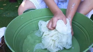 Kızın elleri bahçedeki yeşil metal bir leğende beyaz çarşafları yıkıyor.