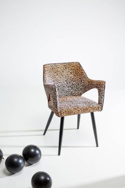Beyaz arka planda leopar desenli sandalye ve siyah balonlar.