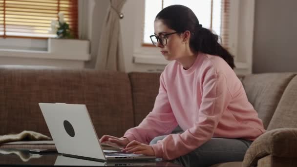自由职业和远程工作 年轻的高加索女人坐在沙发上 在笔记本电脑上打字的肖像 在总公司工作的家庭主妇 — 图库视频影像
